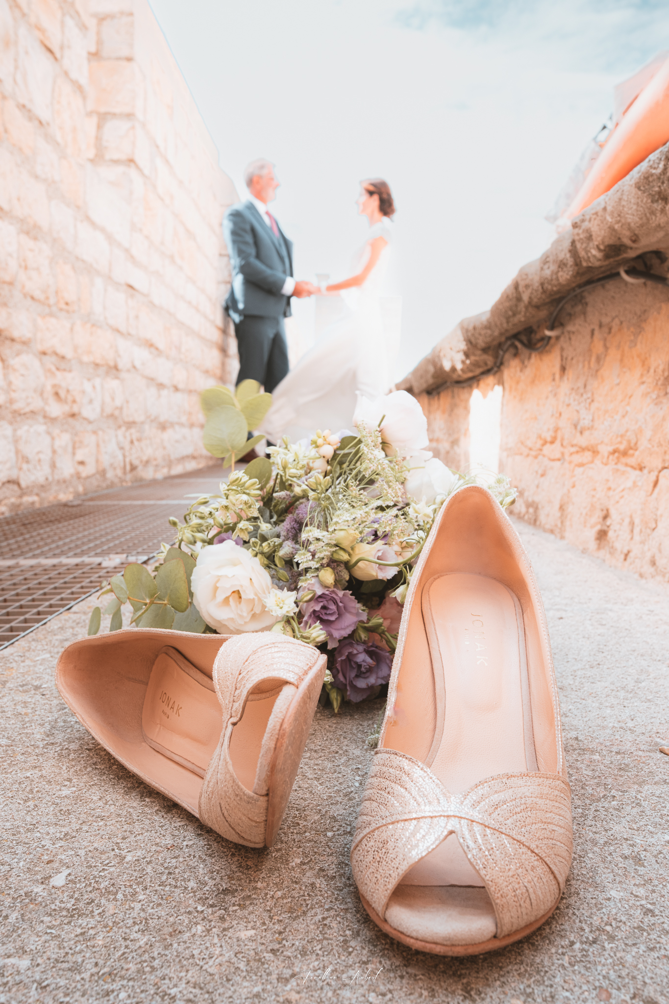 Détails de mariage avec chaussures, bouquet et couple en arrière-plan