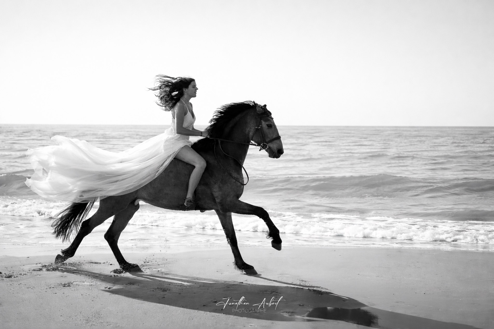 Mariée à cheval sur la plage, photographie noir et blanc signée Jonathan Aubert