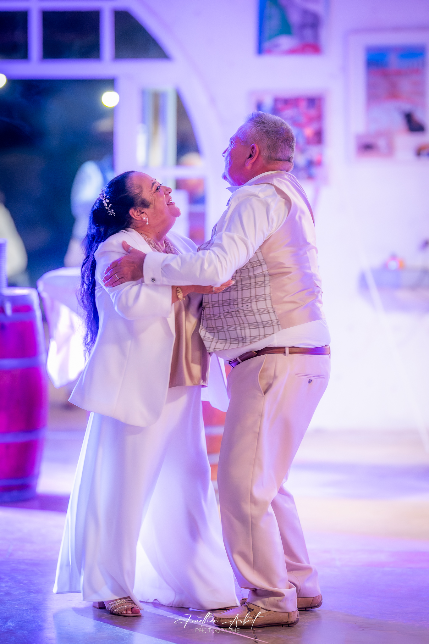 Couple de mariés dansant lors de la réception, éclairage violet et rose de salle de mariage
