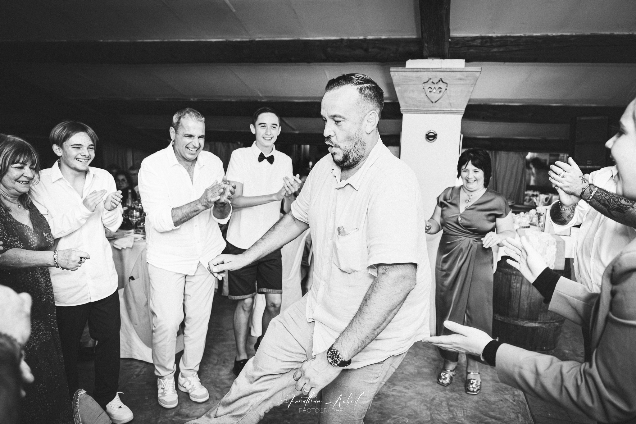 Marié dansant avec ses amis et famille lors de la réception, ambiance festive en noir et blanc